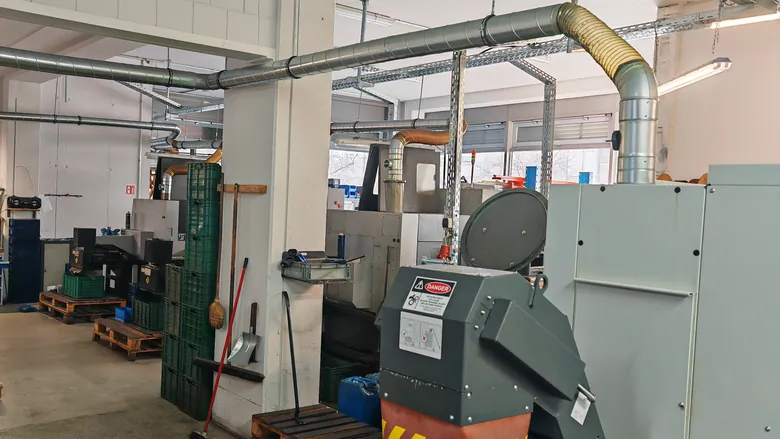 Werkstatthalle mit Maschinen, Rohrleitungen und Materialkisten – Handwerksbetrieb im Alltag